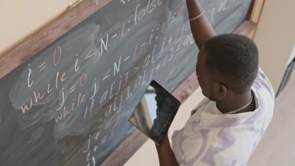 美国黑人男生在大学课堂上观看数码平板电脑和在黑板上书写脚本的高角镜头 — 图库视频影像