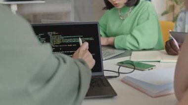 Erkek ve kız öğrencilerin ellerinin bilgisayar ekranını göstererek ve ders sırasında programlama kodlarını tartışarak yakın plan çekimleri.