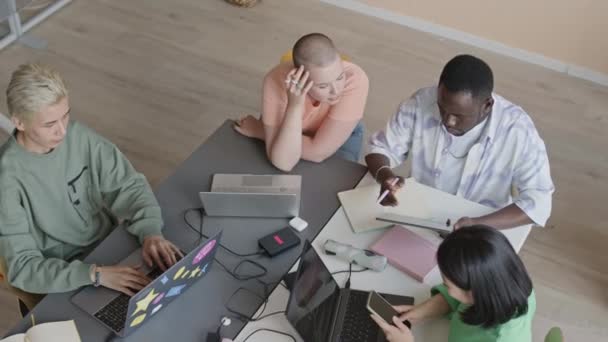 在大学课堂上 一群年轻的多民族学生围坐在桌旁 在笔记本电脑上进行编码 并在编程课上使用数字平板电脑的高视角图像 — 图库视频影像