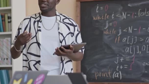 Przycięte Ujęcie Afroamerykańskiego Nauczyciela Trzymającego Cyfrową Tabletkę Stojącego Obok Tablicy — Wideo stockowe