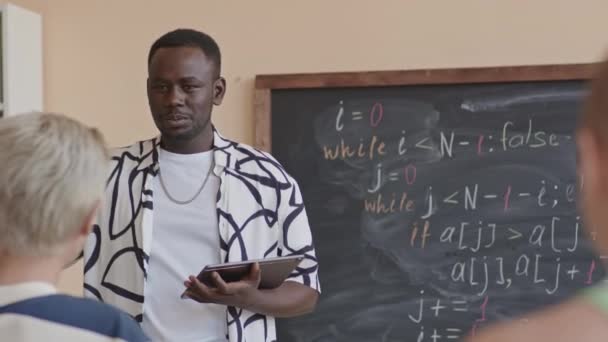Młody Afroamerykanin Trzyma Cyfrowy Tablet Rozmawia Kolegami Grupy Stojąc Przy — Wideo stockowe