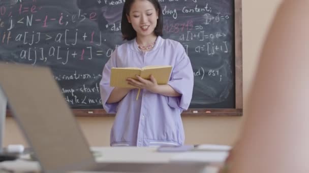 Przechyl Się Ujęcie Młodej Azjatyckiej Studentki Czytającej Notatki Kolegom Grupy — Wideo stockowe