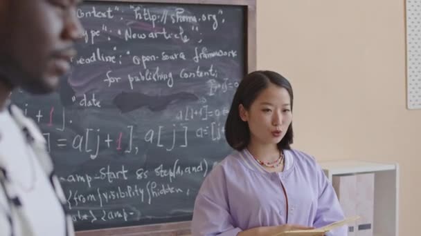 Young Asian Female Teacher Standing Chalkboard Speaking African American Student — Stock Video