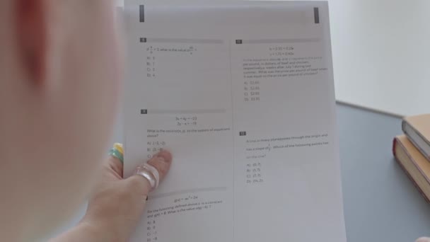 Через Плечо Девушка Колледжа Читает Тестовые Вопросы Бумаге Сидя Столом — стоковое видео