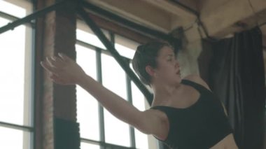 Düşük açılı orta açılı sanatsal genç bayan modern dansçının akışkan hareketler yaptığı, stüdyo stilinde serbest dans ettiği.