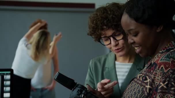 スタジオでファッション写真撮影中にチームで働いている間 クリエイティブディレクターとカメラで画像を議論する黒人女性写真家 — ストック動画