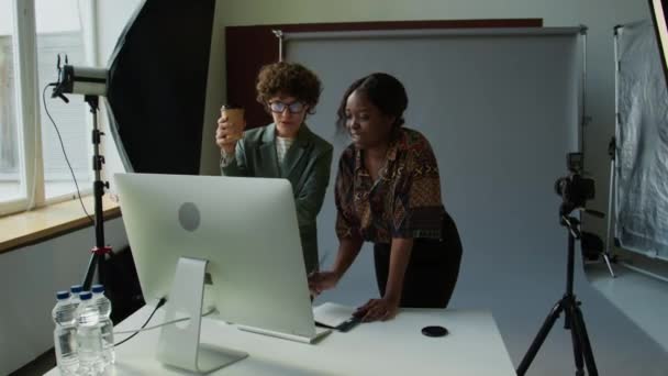 女性艺术指导和摄影师站在桌子后面 看着电脑屏幕 讨论工作室里的摄影结果 — 图库视频影像