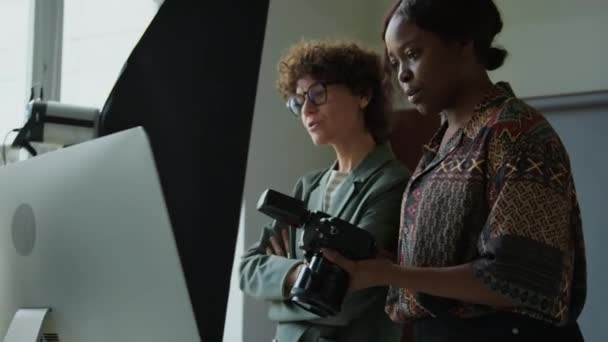 年轻多样的女性摄影师和创意总监检查相机和电脑上的照片 并在工作室讨论拍摄日 — 图库视频影像