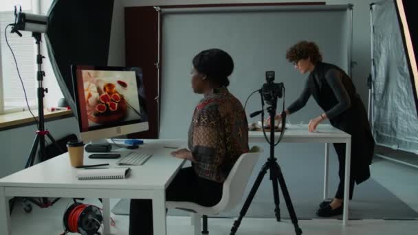 Афроамериканка Фотограф Масштабирует Изображение Инжира Компьютере Дает Инструкции Кулинарному Стилисту — стоковое видео