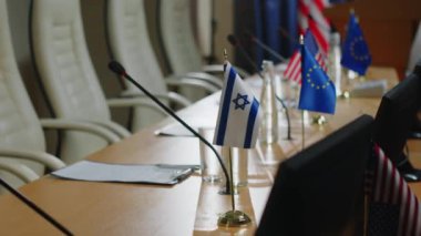 Konuşmacılar için hazırlanan basın masasında İsrail, ABD ve Avrupa Birliği bayrakları