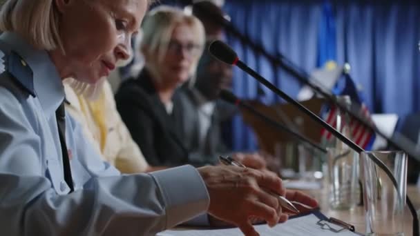Kadın Askeri Görevlinin Mikrofonla Masaya Oturduğu Uluslararası Basın Toplantısı Sırasında — Stok video