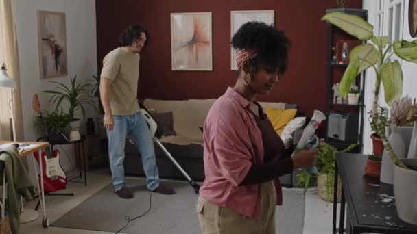 在现代公寓里 一对年轻的跨种族夫妇一起做家务活的中景照片 用微纤维布擦拭表面 用吸尘器吸尘的白人男子的照片 — 图库视频影像