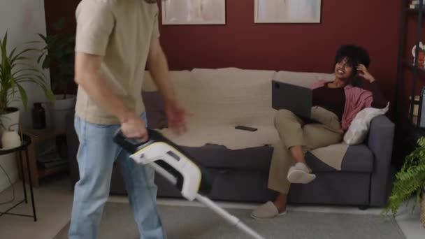 Tilting Shot Young Caucasian Man Hoovering Carpet Cozy Studio Apartment — Vídeos de Stock