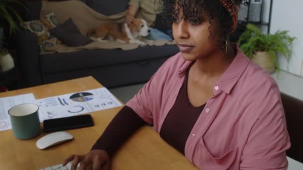 年轻成功的伯利兹女商人坐在台式计算机前 一边在家工作一边打电话 一边与白人丈夫和他们的狗呆在一起 — 图库视频影像