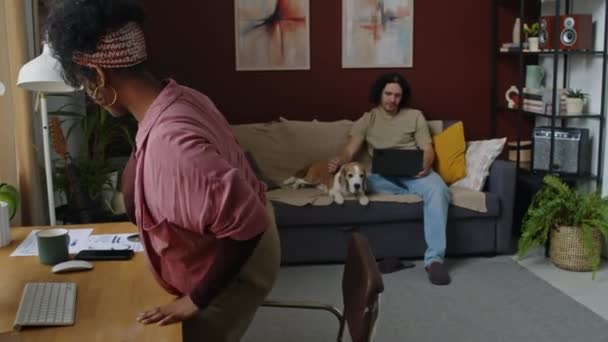 中镜头 年轻的比利西亚女人在电脑上休息 坐在沙发上 与她的白人丈夫和他们可爱的小猎犬在一起 — 图库视频影像