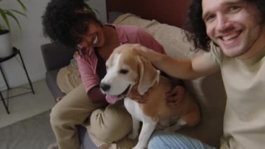 Kafkas asıllı genç bir adamın Melez kız arkadaşı ve köpeğiyle boş zamanlarında modern dairede kanepede otururken çekilmiş bir görüntüsü.