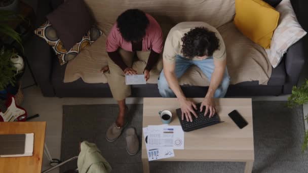 디지털 태블릿과 노트북 컴퓨터를 거실에서 소파에 청구서를 민족적으로 커플의 — 비디오