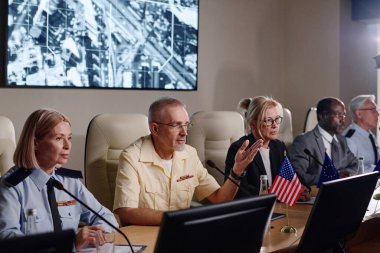 İş adamları mikrofonla konuşuyor ve konferansta otururken ülkedeki zor durumu tartışıyorlar.