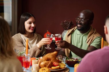 Beyaz kadın ve siyah adam kadeh tokuşturup bayram sofrasında oturuyorlar.