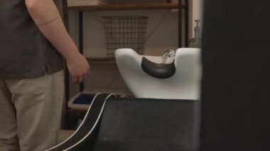 Berber dükkanına dalmaya giden adam, profesyonel berberin yardımıyla oturur ve arkasına yaslanır.