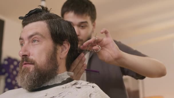 Bearded Man Sitting Hairdressing Salon Speaking Barber Giving Him Haircut — Stock Video