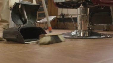 Saçımı kestikten sonra yerleri süpürge ve kepçeyle süpüren tanınmaz hale gelmiş berberin bacaklarını yakın plan çek.