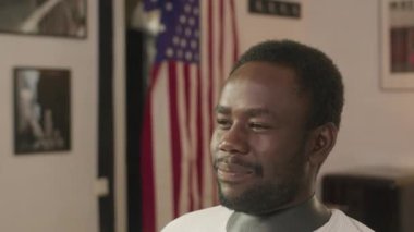 Genç Afrikalı Amerikalı bir adam kuaförde oturuyor ve berberle konuşuyor. Saçını kesiyor.