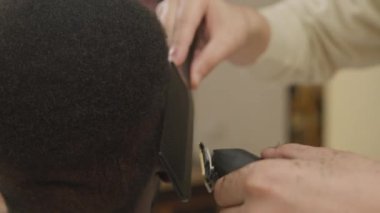 Profesyonel berberin, saç kesme makası ve tarak ile müşterinin saçını keserken yakın plan çekimleri.