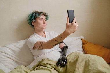 Engelli olan neşeli kız yatakta ve video başında arkadaşını ya da ailesini arıyor.