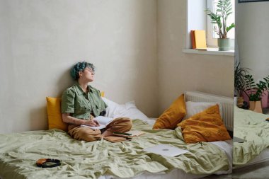 Yorgun öğrenci yatak odasında ödev yaparken uyuyakalmış.