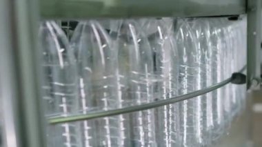 Fabrikadaki konveyörde saf su şişelenmesi için hazırlanan boş PET şişelerini kapatın.