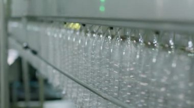 Fabrikada çalışan konveyörde su doldurmak için hazırlanmış boş plastik şişeleri kapatın.