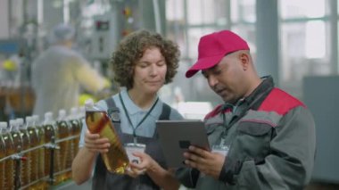 Dijital tablette limonata şişesinin teknik kartını dolduran birkaç fabrika işçisinin orta boy fotoğrafı.