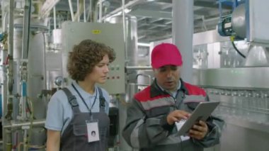 Ustabaşı ve teknisyenin su fabrikasında çalışan dijital tablete bakarak üretim hacmini tartışırken çekilen görüntüler.