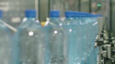 Saf damıtılmış suyla PET şişelerinin odak noktası içecek fabrikasındaki otomatik taşıma hattında hareket ediyor.
