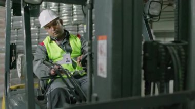 Erkek yükleme makinesi operatörünün içecek deposunda çalışmasının orta derecede uzun bir yolu.