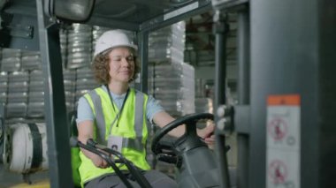 İçki fabrikasında çalışırken paletleri özel ekipmanlarla yüklerken orta boy bir depo çalışanı görüntüsü.