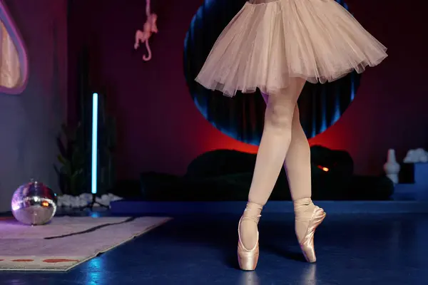 Legs of ballerina in pointe shoes posing on tiptoes in contemporary art studio