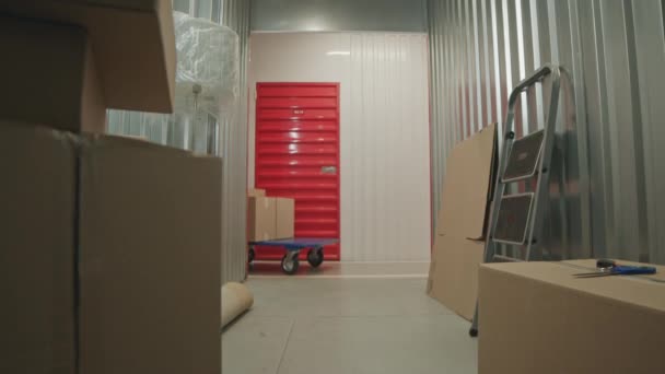 倉庫の箱が付いている人形のカートを押す人の自己貯蔵の単位の内部からの眺め — ストック動画