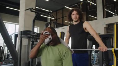 Ciddi erkek atlet ve orta yaşlı sporcunun portresi. Alnından terini havluyla siliyor ve spor salonundaki kameraya bakıyor.