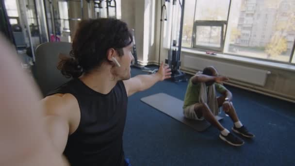 男子健身博主与朋友一起带着无线耳机拍摄体操视频的Pov照片 — 图库视频影像