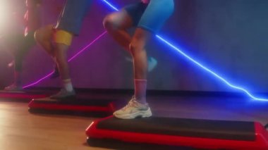 Aerobik dersinde neon ışıklarla atölyede eski tarz adımlar atan üç aktif sporcunun çekimini kaldır.