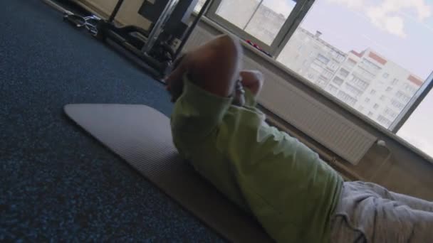친구가 체육관에서 다리를 잡고있는 바닥에 복근을하는 중년의 남자의 휴대용 — 비디오