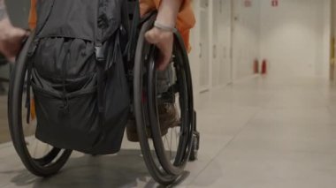 Sırt çantalı, tekerlekli sandalyeli, tanınmayan bir adamın arka plan görüntüsü.