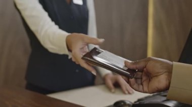 Oteldeki kayıt masasının müdürüne pasaport veren tanınmayan bir adamın yakın çekimleri.