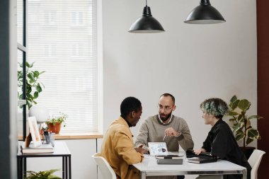 Genç iş adamları ofiste otururken tablet ekranda grafikleri ve grafikleri tartışıyor