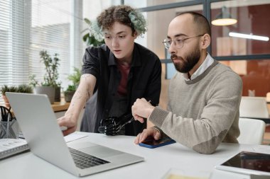 Erkek ve protezli kadın meslektaşı ofis masasında birlikte çalışıyorlar.