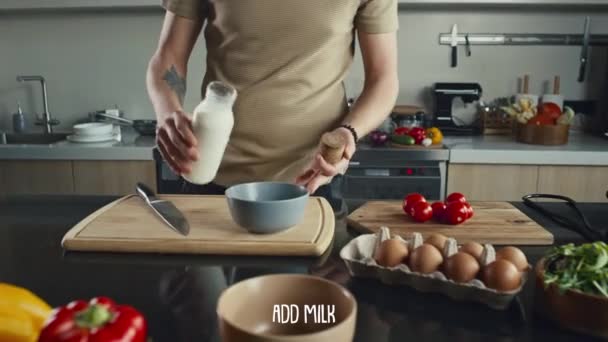 認識できないシェフの手の近くのビュー ボウルにミルクを追加し キッチンテーブルで食事を調理しながら成分を白くします レシピの説明と字幕は 以下に表示されます — ストック動画
