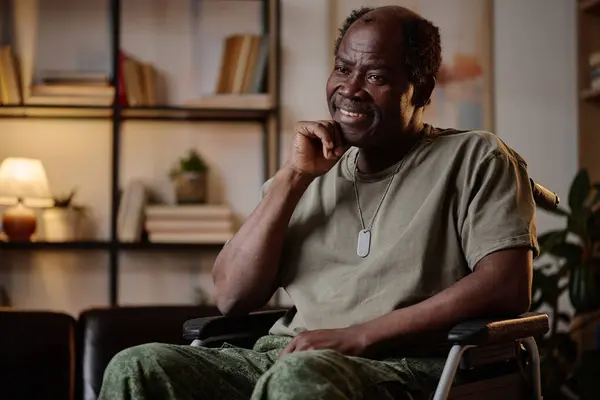 Cheerful senior african american war veteran in military uniform sitting in wheelchair