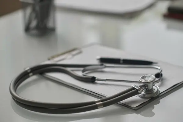 Closeup of stethoscope and medical record on clipboard placed on hospital table, copy space